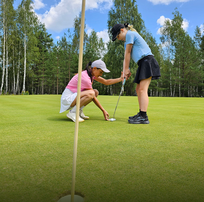 AGG Our Mission - Instructor Helping Girl Learn How to Putt